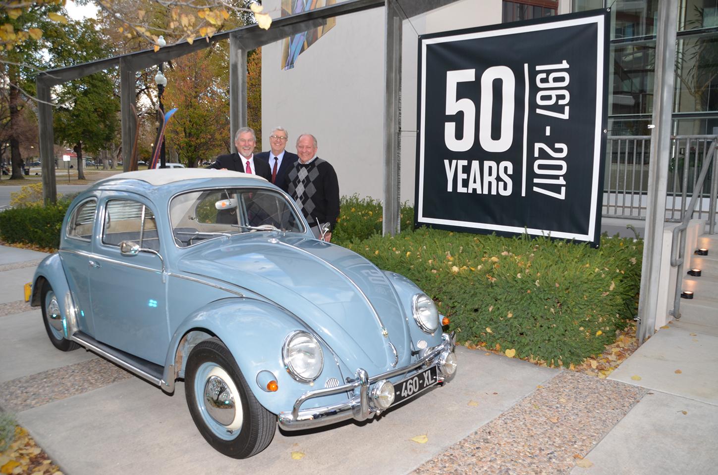 Dee Livingood's original three young lions in 2017, standing behind a light blue Volkswagen Beetle.